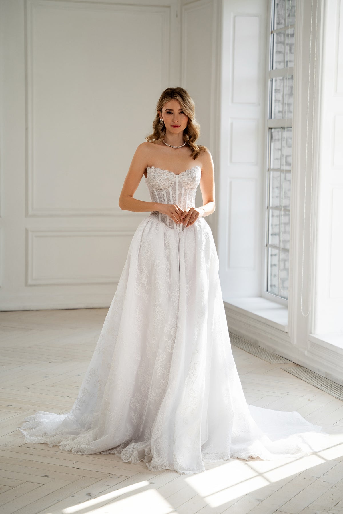 Bride in strapless corset wedding dress with lace skirt and thigh slit, front view