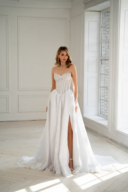 Bride in strapless corset wedding dress with lace skirt and thigh slit, front view