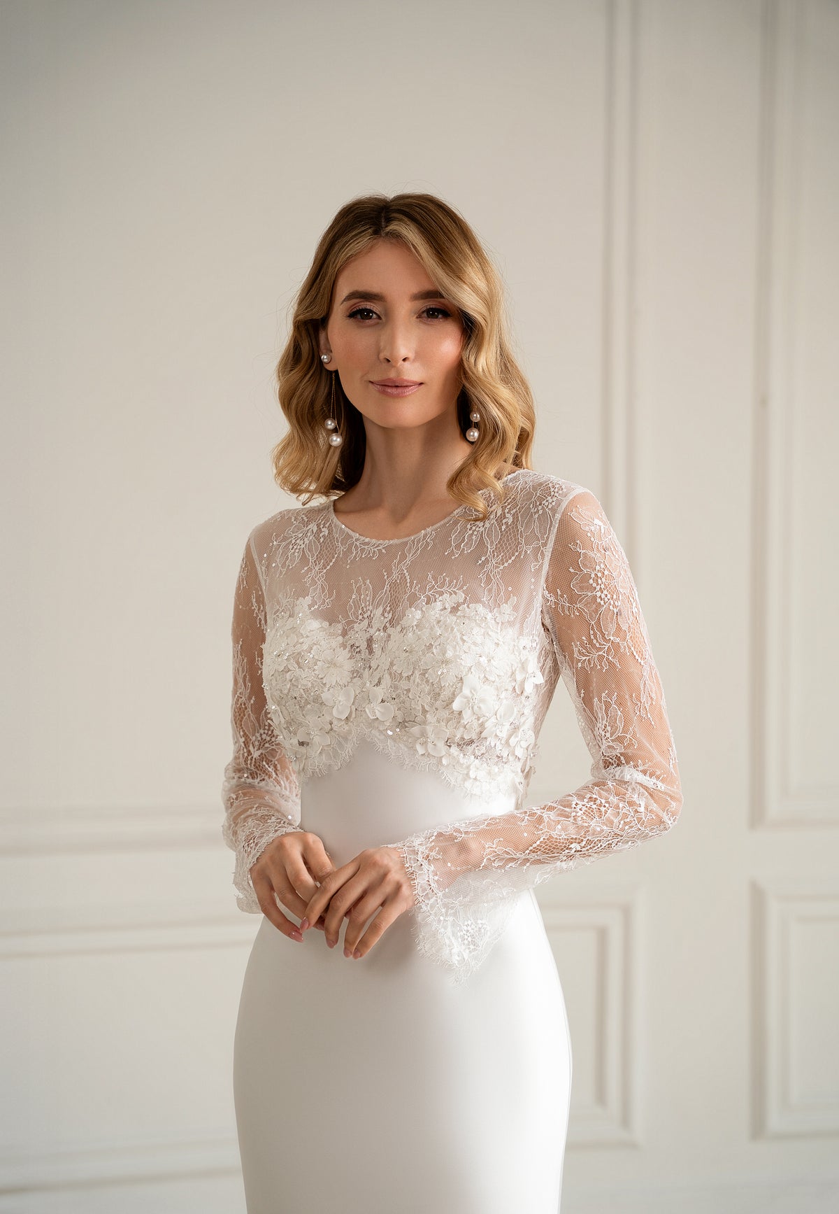 "Bride in long sleeve lace wedding dress with 3D floral bodice, front view"