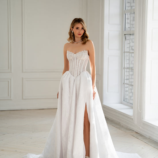 Bride in strapless corset wedding dress with lace skirt and thigh slit, front view
