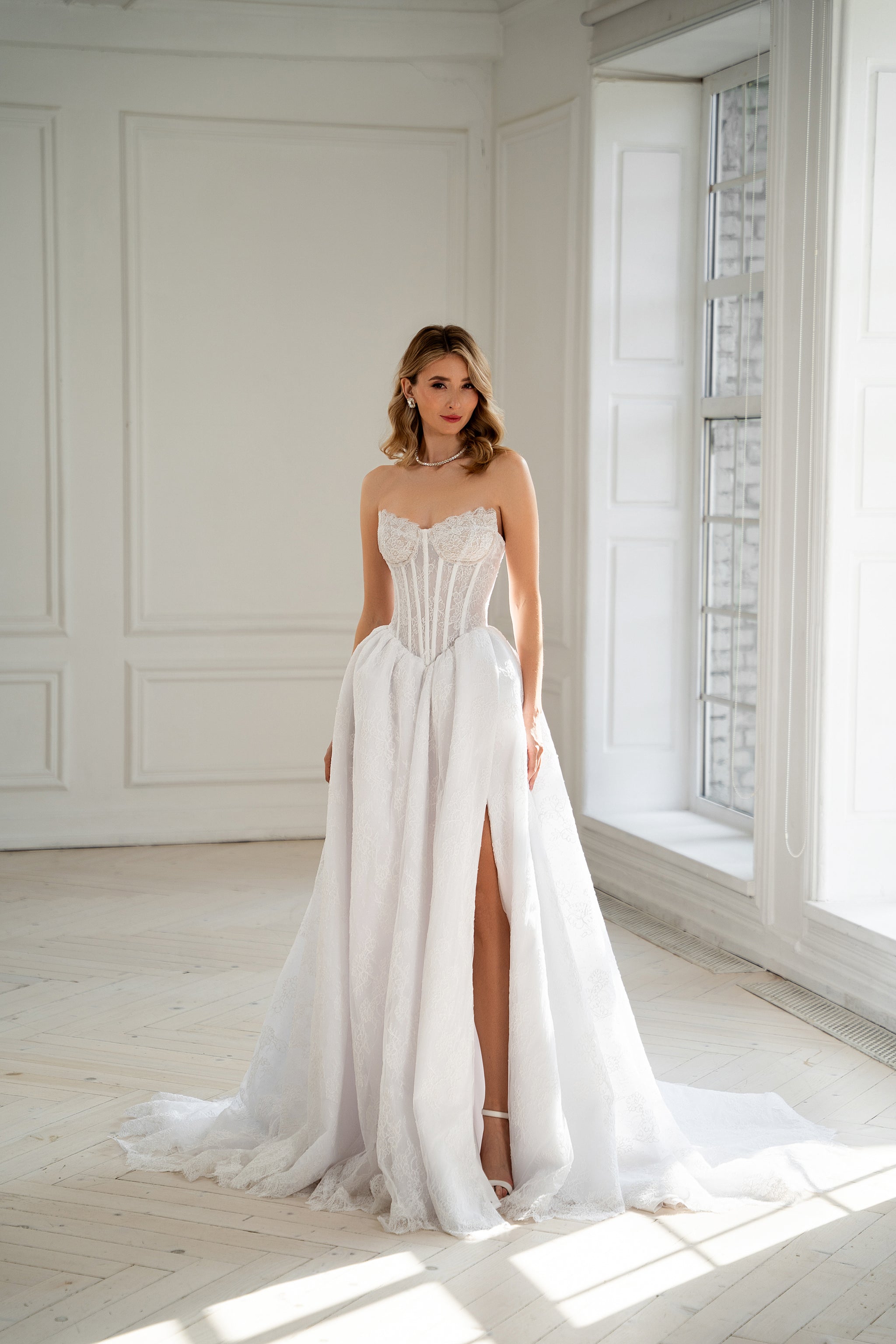 Bride in strapless corset wedding dress with lace skirt and thigh slit, front view